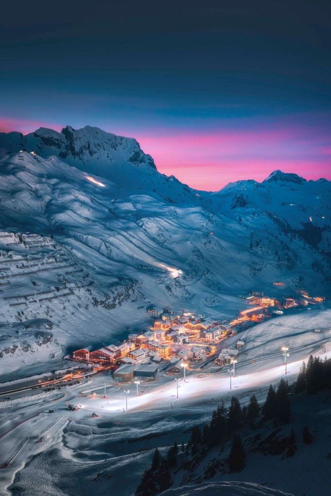 Schneedorf unter violettem Abendhimmel.