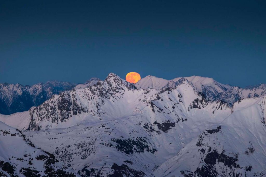 Voller Mond über Alpengipfeln.