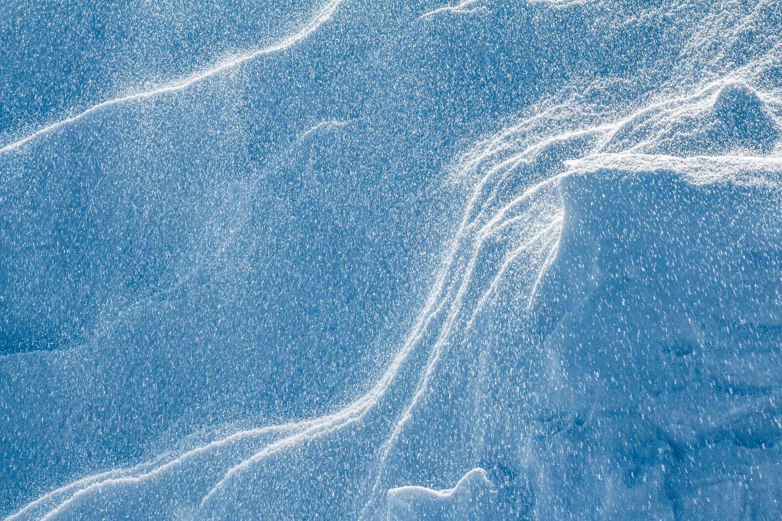 Wirbelnder Schnee auf eisblauem Landschaft.