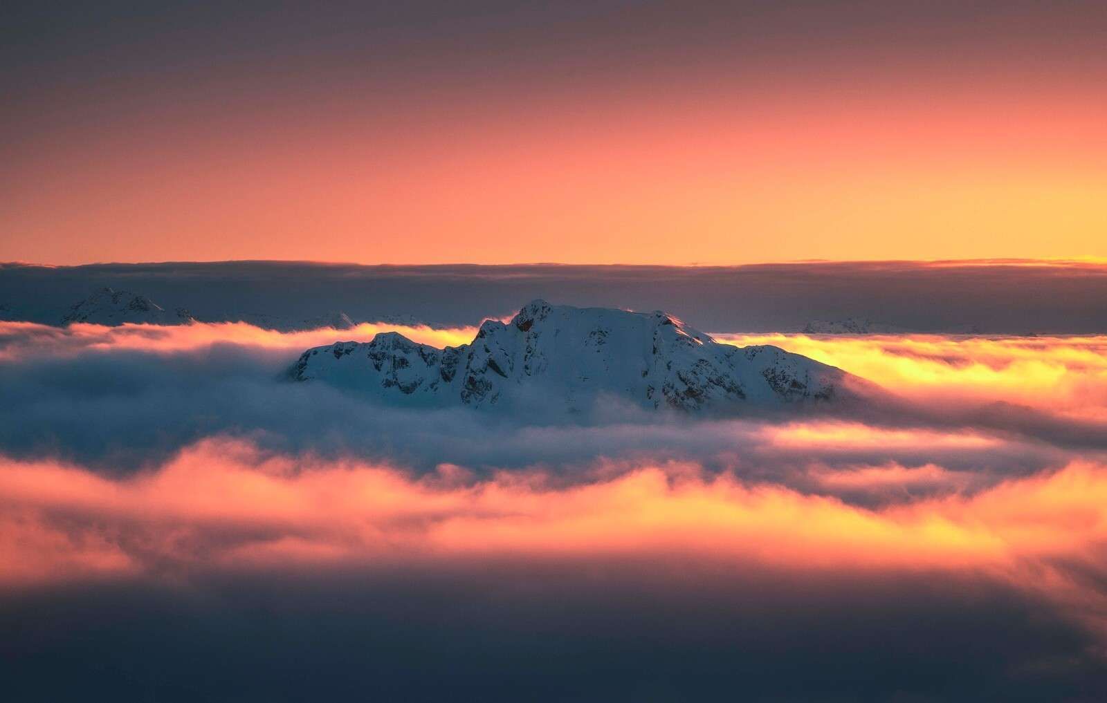 Schneebedeckter Berggipfel im Wolkenmeer.