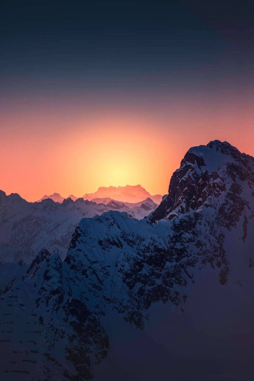 Besneiter Berggipfel bei feurigem Sonnenaufgang
